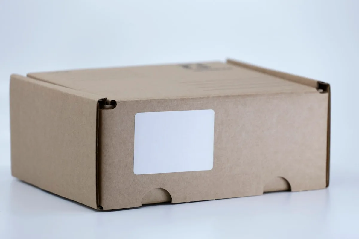 A brown kraft shipping box with a blank white peel-and-stick label, ready for a label printer to fill