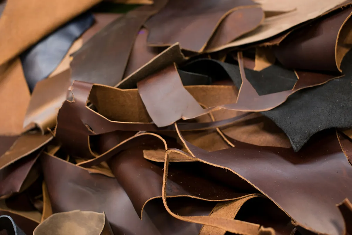 A heap of leather offcuts in shades of brown, tan and black, their trimmed edges curling over one another