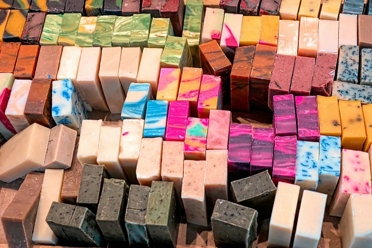Dozens of freshly cut handmade soap bars in swirled colors, stood on edge in rows across a wooden curing board