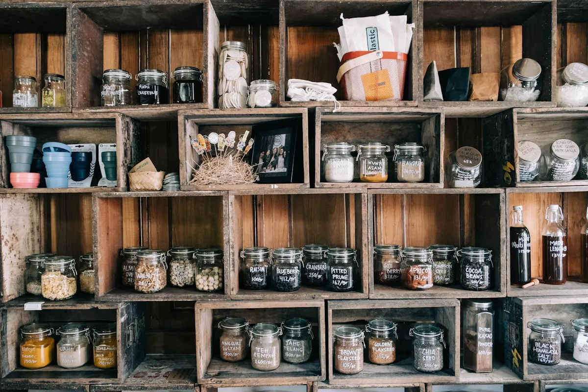 Rustic wooden crate shelving filled with labeled glass jars of ingredients and supplies in a maker workshop